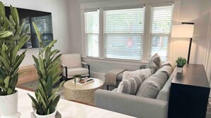 A living room with a sofa, a coffee table, and two potted plants. - Luxe Victorian 2BR/2BA Downtown w/Serene Backyard (Sacramento)