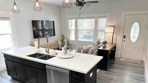A modern kitchen with a central island, black cabinetry, stainless steel appliances, and pendant lighting. - Luxe Victorian 2BR/2BA Downtown w/Serene Backyard (Sacramento)