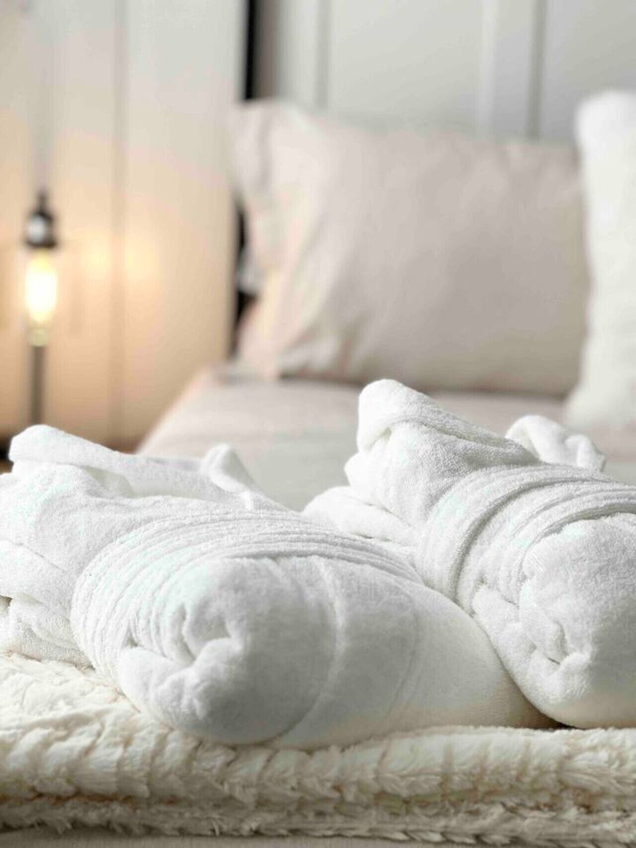 A neatly made bed with white linens and a fluffy white blanket.