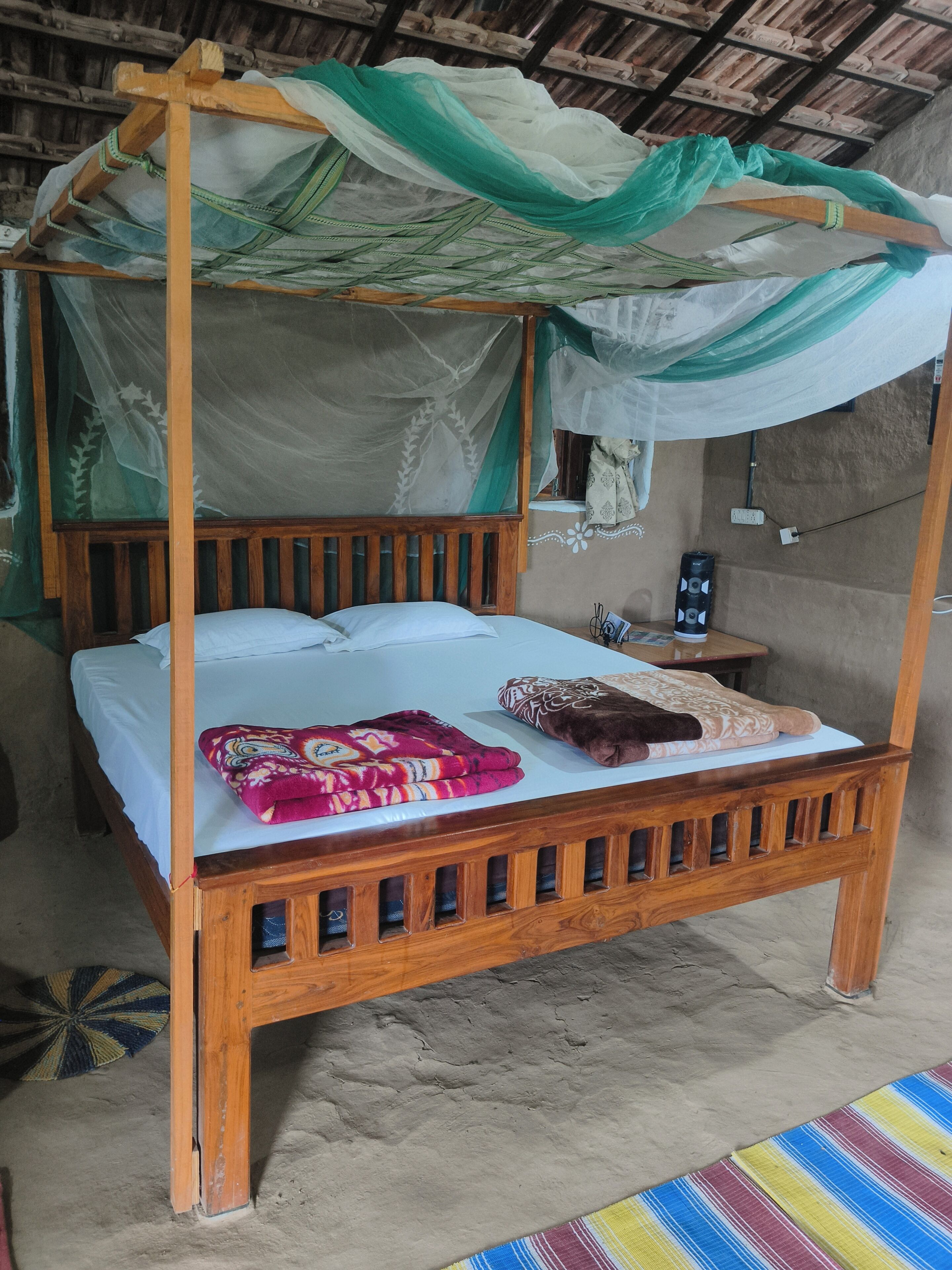 A wooden bed with a canopy, a bedside table, and a wall socket.