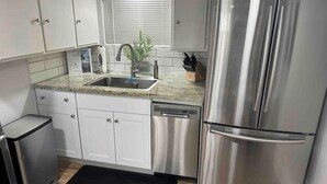 Een moderne keuken met roestvrijstalen apparatuur, witte kasten en een zwart vloerkleed.