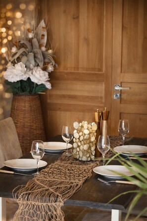 A wooden dining table set with plates, wine glasses, and a decorative centerpiece.