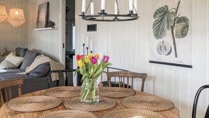 Ein Esstisch mit gewebten Tischsets, einer Tulpenvase und einer Kristallleuchter.