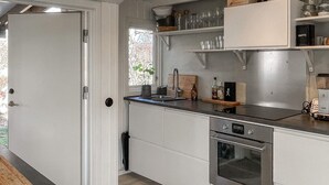 Eine moderne Küche mit weißen Schränken, einem eingebauten Ofen und einer Arbeitsplatte mit verschiedenen Küchenutensilien.
