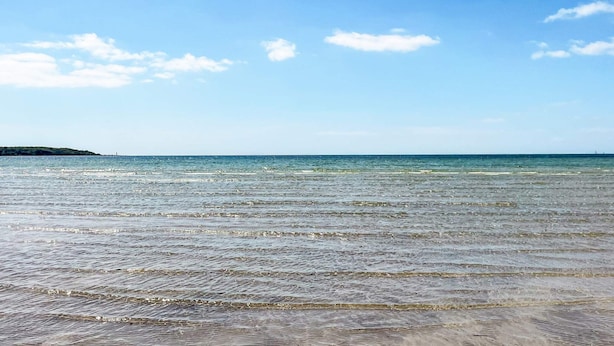 Ein Strand mit klarem Wasser und einer entfernten Küstenlinie.