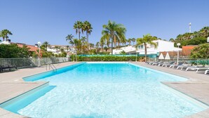 A rectangular swimming pool with clear blue water, surrounded by a tiled deck.