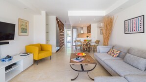 A modern living room with a sofa, a yellow armchair, a coffee table, and a TV on a stand.