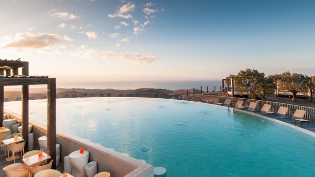 An infinity pool with a view of the coastline, lounge chairs, and tables. - Villa in Salobre Golf with Private Pool (San Bartolomé de Tirajana)