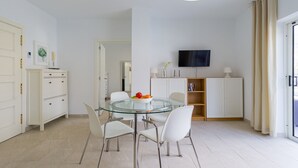 A modern kitchen with white cabinets, a glass dining table, and a flat-screen TV mounted on the wall. - Apartment in Mogán Playa near the Beach (Mogán)