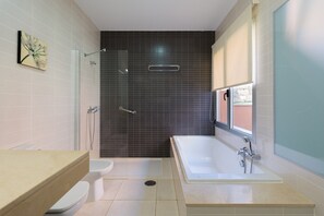 A modern bathroom with a bathtub, toilet, and shower.