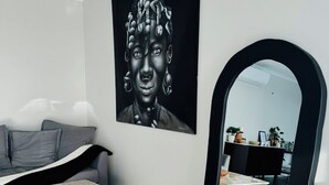 Una sala de estar moderna con un sofá gris, una mesa de centro, un cuadro grande en blanco y negro, y un espejo con marco negro.