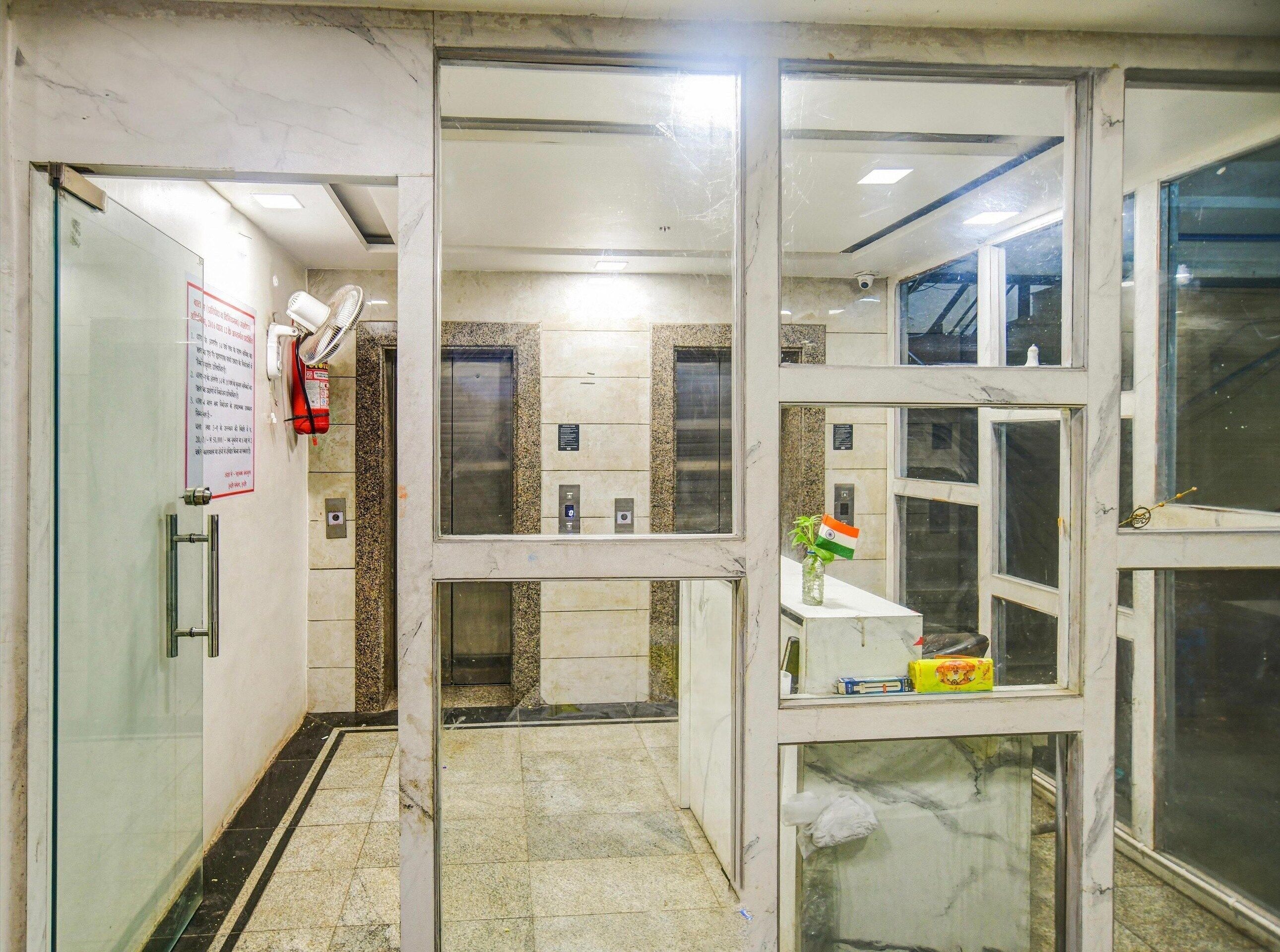 An elevator area with marble walls, glass doors, and an Indian flag decoration.