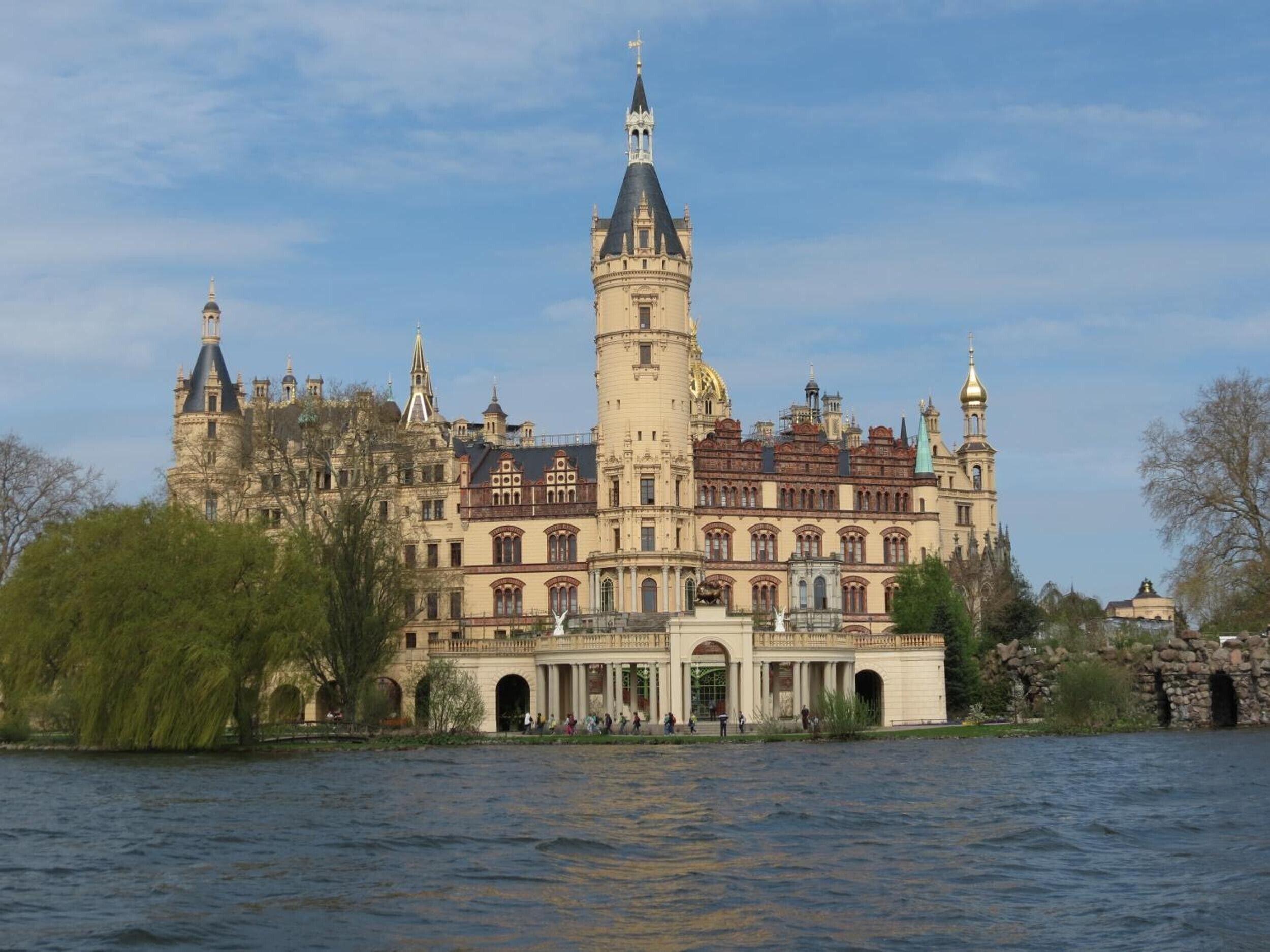 Ein historisches, schlösserartiges Gebäude mit einem markanten Turm, gelegen am Wasser.