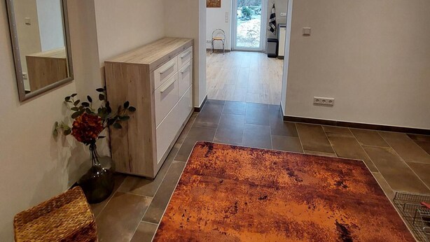 A modern interior with a wooden dresser, a mirror, a vase with flowers, and a patterned rug. - Holiday Apartment 'Quiet and Central' with Wi-Fi (Schwerin)