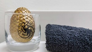 Un saladier en verre transparent contenant un objet doré, placé à côté d’une serviette bleu foncé pliée.