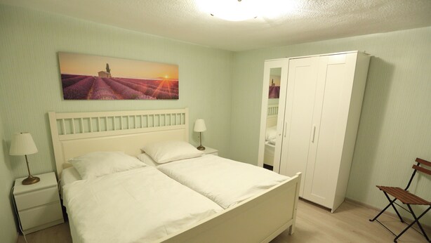 A bedroom with a bed, nightstands, a wardrobe, and a bench.