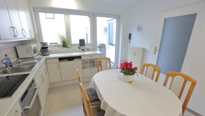 A compact kitchen with white cabinets, a microwave, a coffee maker, and a dining table with four chairs.