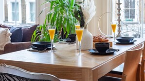 A breakfast table with orange juice, a croissant, and a vase of pampas grass.