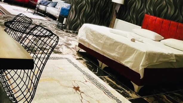 A modern hotel room with a large bed, a red sofa, a white sofa, and a black chair. - NERA OTEL (Istanbul)