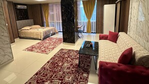 A spacious room with a large bed, a sofa, and a small table. There are two air conditioning units on the walls, and a window with curtains. - NERA OTEL (Istanbul)