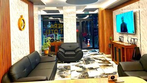 A modern lobby with black leather sofas, a large TV screen, and a marble-patterned floor. - NERA OTEL (Istanbul)