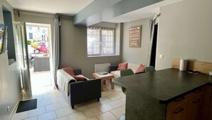 A modern living room with a sofa, a dining table, and a kitchen area with a counter and cabinets.
