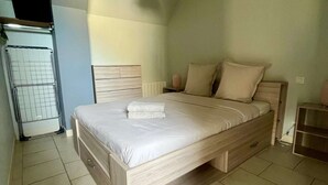 A bedroom with a large bed, a radiator, and a hanging light fixture.