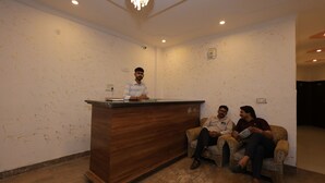 A reception area with a wooden desk, two sofas, and a chandelier. - Hotel ZoVo Agra (Agra)
