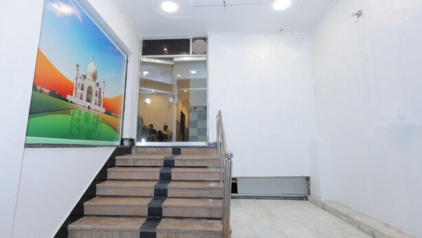 A staircase with a handrail leading to a room with a glass door. - Hotel ZoVo Agra (Agra)
