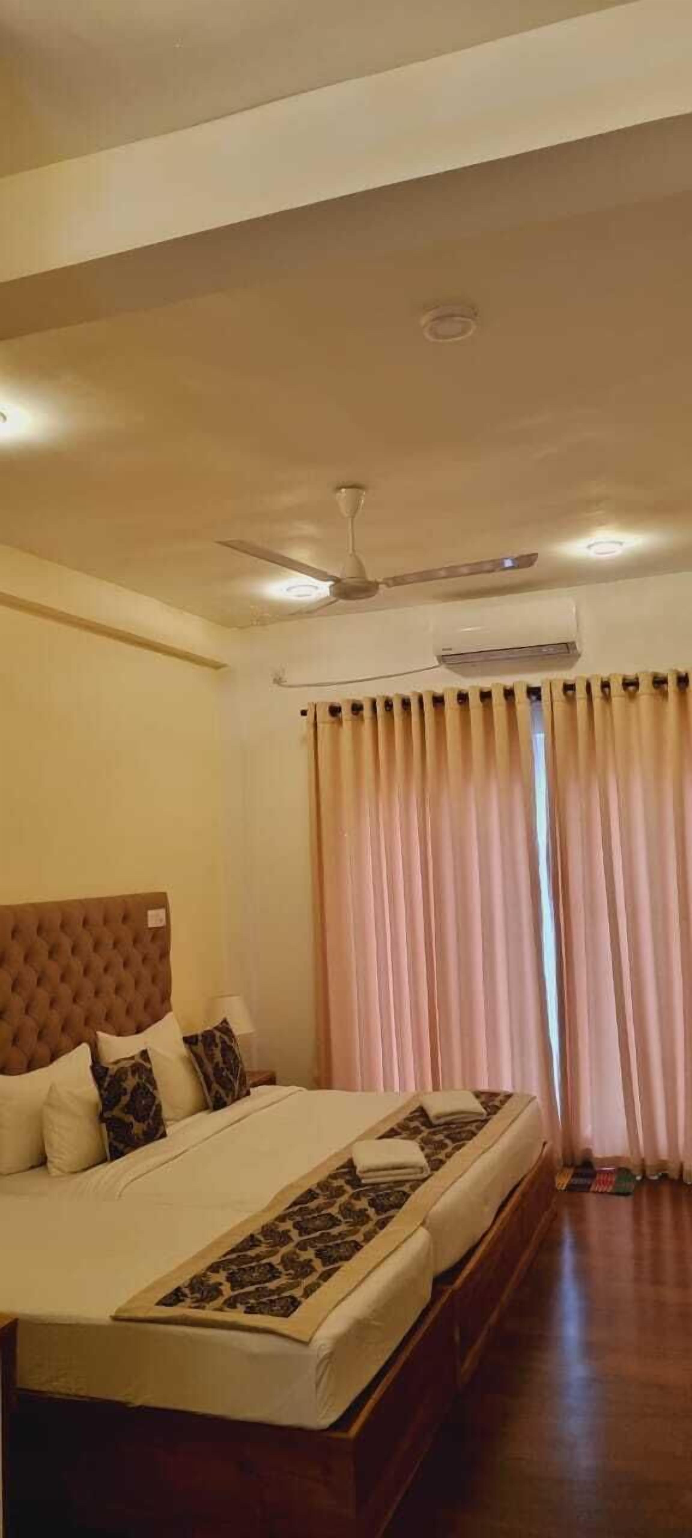 A bedroom with a large bed, a ceiling fan, and a window with curtains.