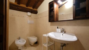 Une salle de bain équipée d’un bidet, de toilettes et d’un lavabo avec un miroir au-dessus.