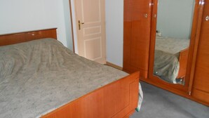 Une chambre à coucher avec un lit en bois, une armoire et un miroir.