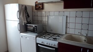 Une cuisine compacte équipée d’un réfrigérateur, d’un four à micro-ondes, d’une cuisinière à gaz et d’un évier.
