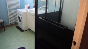 Une petite salle de bain équipée d’un lave-linge, d’un lavabo et d’un miroir.