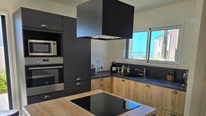 Een moderne keuken met een inbouwoven, magnetron en een groot kookeiland.