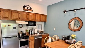 A kitchen with wooden cabinets, stainless steel appliances, and a dining area with wooden chairs.
