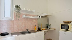A compact kitchen with a sink, countertop, and a microwave on a small refrigerator. - Sunrise (Corfu)