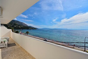 Ein Balkon mit Meerblick, ein gepflasterter Weg und ein ferner Gebirgszug.
