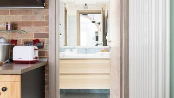 A modern kitchen with a toaster, a sink, and a window overlooking a bathroom.