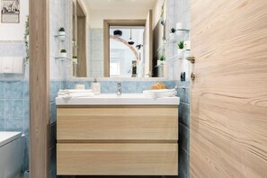 Un baño moderno con tocador de madera, lavamanos y espejo.