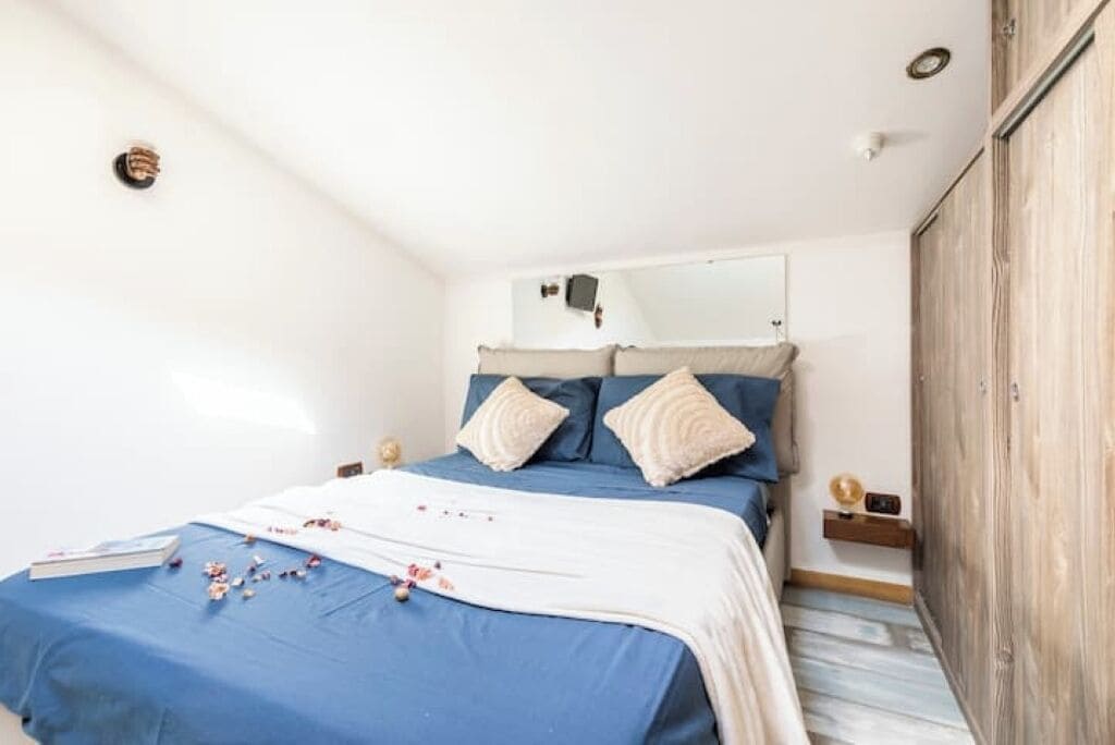 Une chambre à coucher avec un lit, des oreillers, une table de chevet et une armoire.