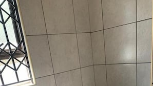Een badkamer met een witte wasbak, toilet en een raam met metalen tralies.