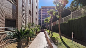 A pathway flanked by buildings and greenery, leading to a high-rise apartment building. - BULEVAR rooftop apartment (La Vila Joiosa)