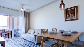 A dining area with a wooden table set for four, a sofa, and a ceiling fan. - BULEVAR rooftop apartment (La Vila Joiosa)