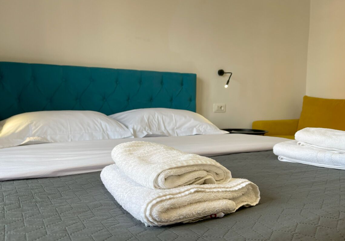 Una cama bien hecha con sábanas blancas y un cabecero color turquesa.