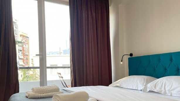A hotel room with a bed, a view through the window, and a balcony. - Cozy studio with WiFi and AC in nice Tiranë (Tiranë)