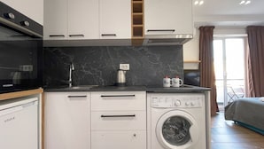 A compact kitchen with a built-in washing machine, a microwave, and a dishwasher. - Cozy studio with WiFi and AC in nice Tiranë (Tiranë)