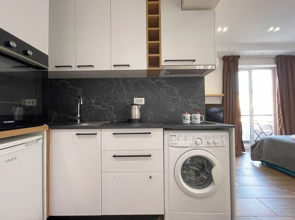 A compact kitchen with a built-in washing machine, a microwave, and a dishwasher.