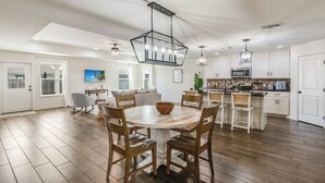 Una cocina amplia con una isla central, sillas de madera e iluminación colgante.