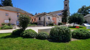 Ein Innenhof mit einem Kirchturm, umgeben von historischen Gebäuden und gepflegter Bepflanzung.